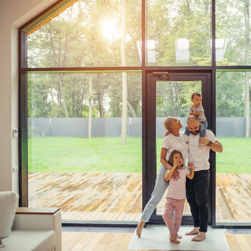 Familie in Haus vor großem Fenster