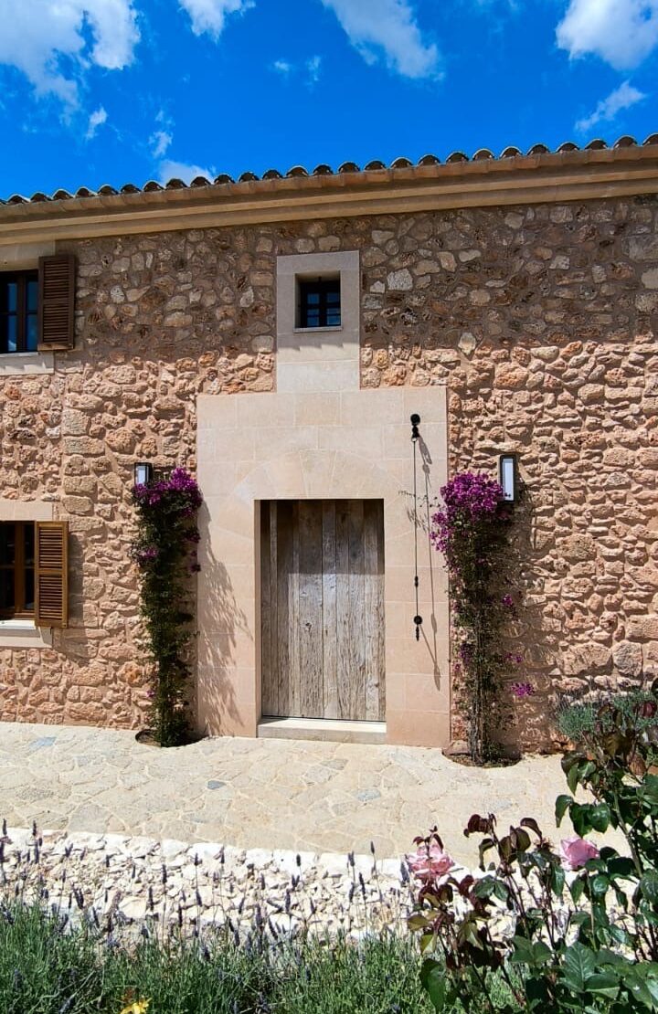 Ein rustikales Steinhaus mit Holztüren und blühenden Kletterpflanzen.