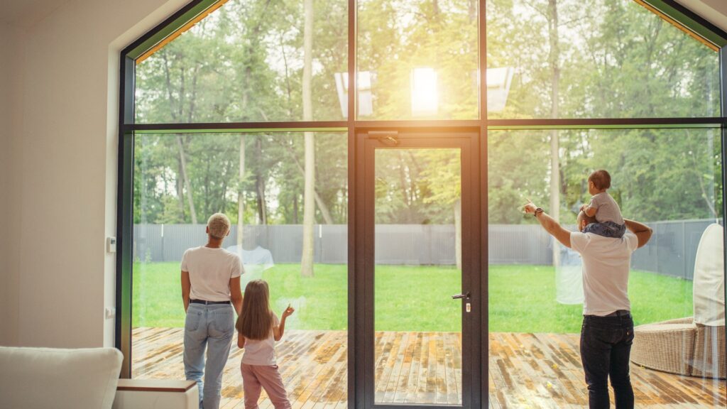 Eine Familie an einer Glasschreibe schauen in den Garten