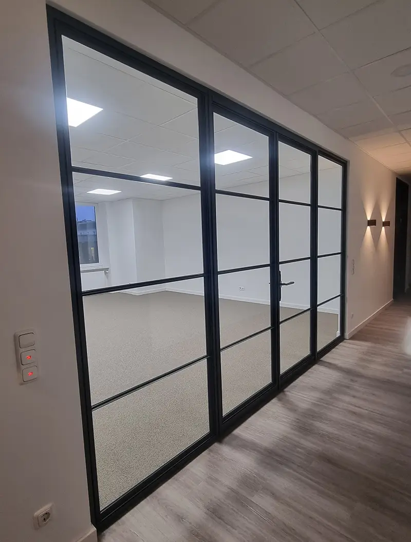 Schwarze Glastrennwand mit Tür, helles Büro, klare Linien, modern