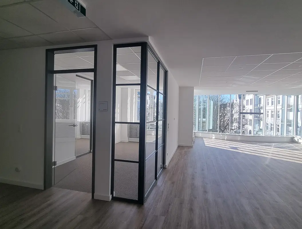 Leeres helles Büro mit Glasraum, grauem Boden und großen Fenstern